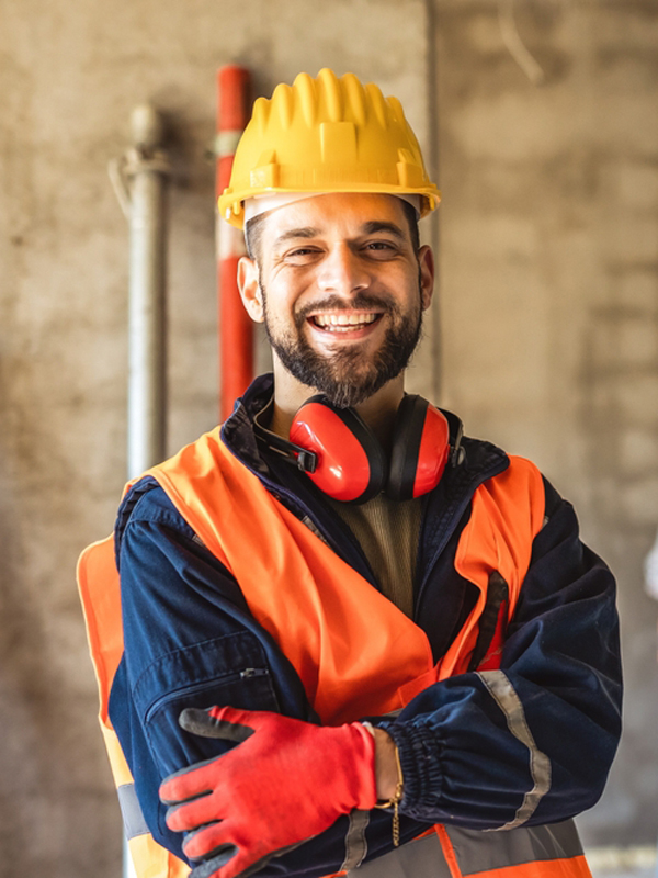 Construction site manager standing wearing safety vest and helmet, thinking at construction site. Young architect watching construction site with confidence.